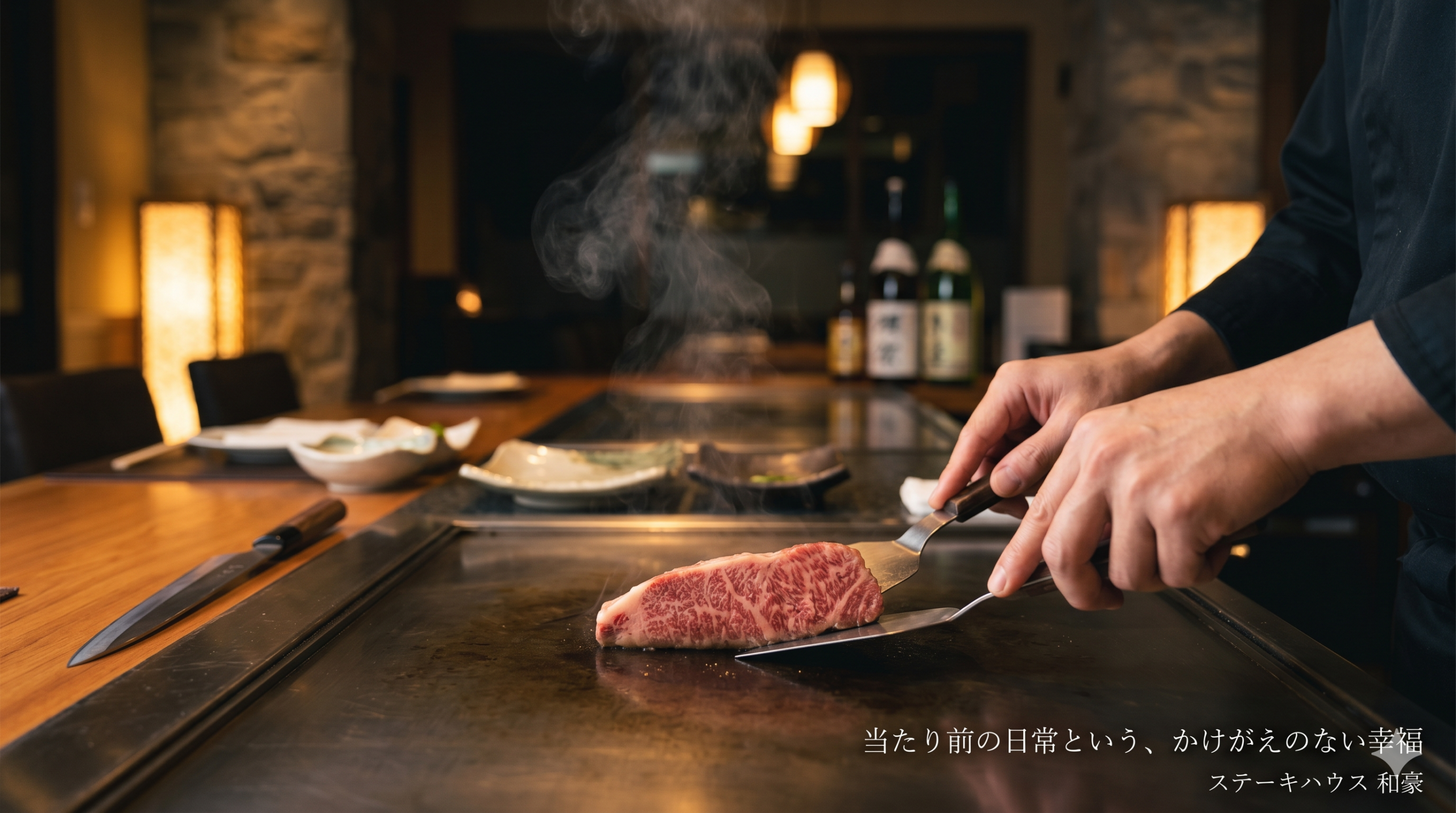 「ステーキハウス和豪の鉄板の上で、美しくサシの入った神戸牛が静かに焼かれている様子。炎や煙はなく、立ち上る微かな湯気と、肉に添えられたシェフの誠実な手元が、日常の平穏と食材への敬意を表現している。」